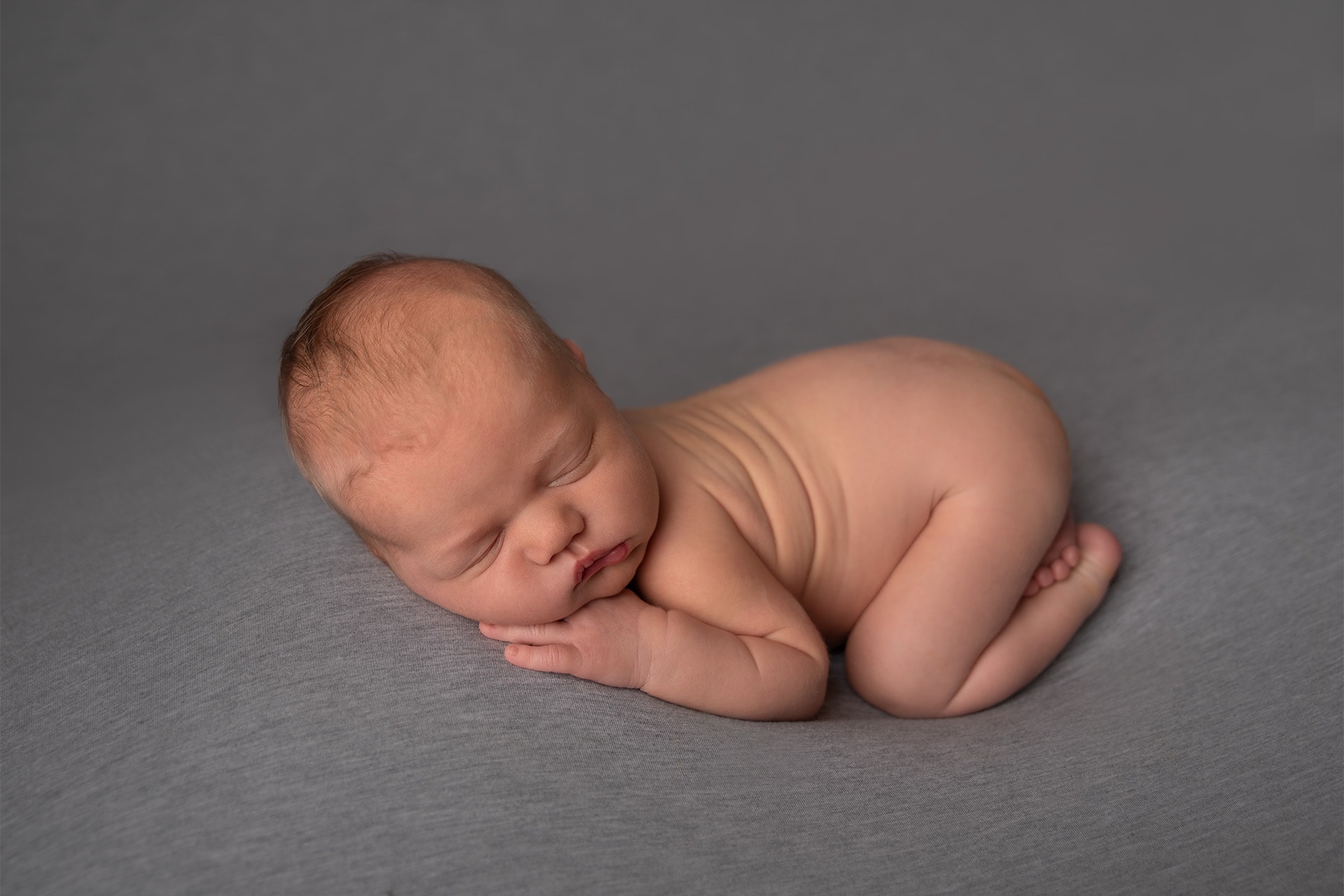 newborn baby boy posed on gray in bismarck studio