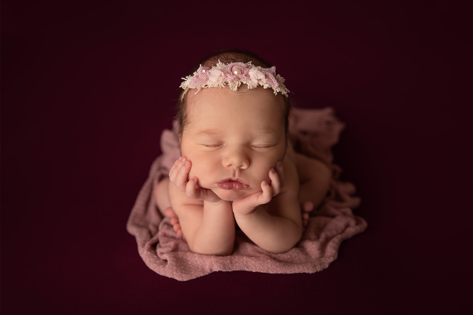 newborn baby girl posed on dark backdrop